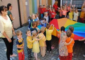 dzieci młodsze ustawione wg kolorów chusty związanych z jesienią na tarasie wraz z nauczycielkami